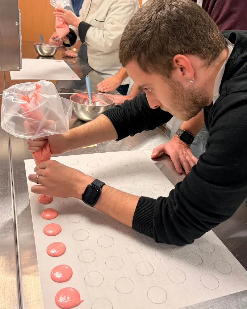 Un collaborateur Ntico dresse des macarons pendant un atelier pâtisserie